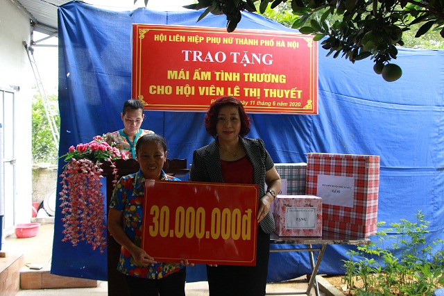 Đồng chí Lê Thị Thiên Hương, Phó Chủ tịch Hội LHPN Hà Nội trao biển tượng trưng kinh phí hỗ trợ chị Thuyết xây Mái ấm tình thương